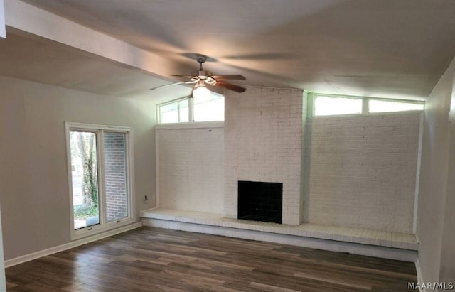 unfurnished living room featuring brick wall, dark hardwood / wood-style flooring, lofted ceiling, and a brick fireplace