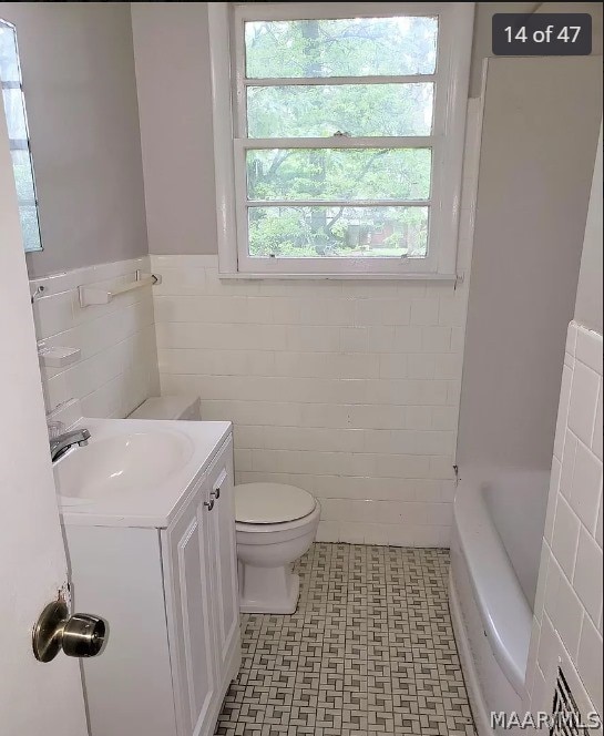 bathroom with vanity, tile patterned floors, toilet, and tile walls