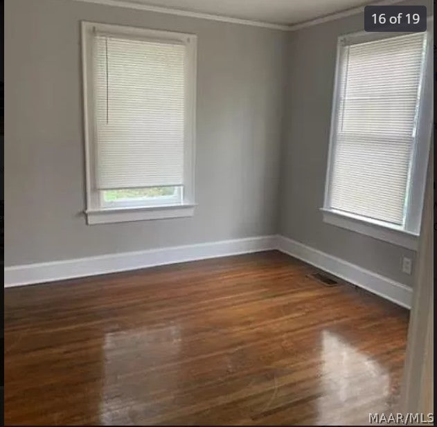 spare room with ornamental molding and dark hardwood / wood-style flooring