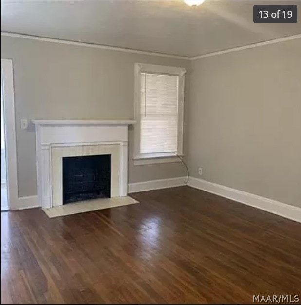 unfurnished living room featuring dark hardwood / wood-style flooring and crown molding