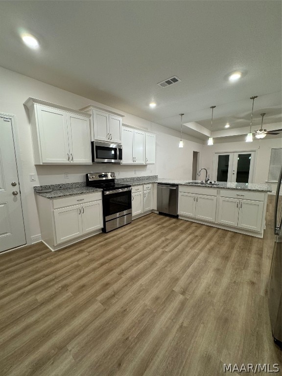 kitchen featuring ceiling fan, light hardwood / wood-style floors, appliances with stainless steel finishes, and kitchen peninsula