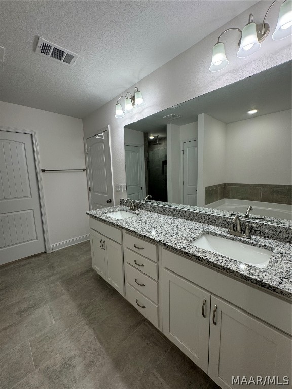 bathroom featuring tile patterned floors, a washtub, a textured ceiling, and double vanity