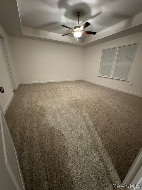 carpeted empty room featuring ceiling fan and a tray ceiling