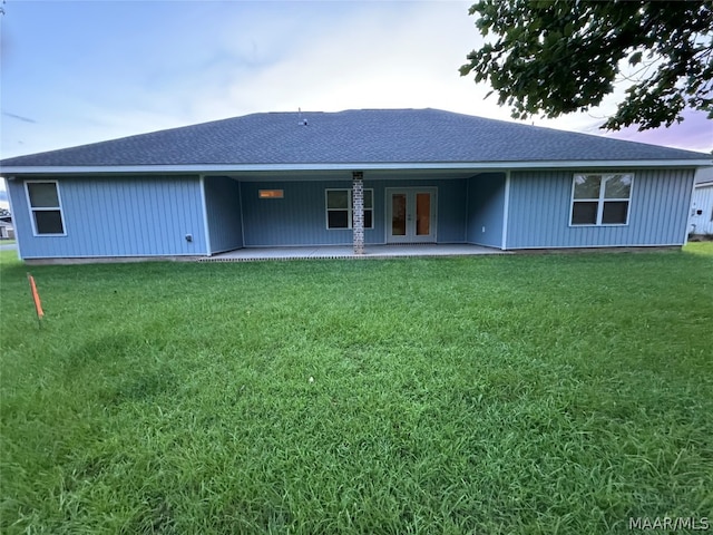 back house at dusk with a patio area and a yard