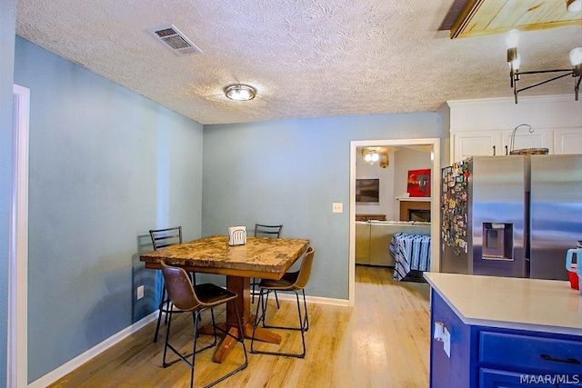 dining room with a textured ceiling and light hardwood / wood-style floors