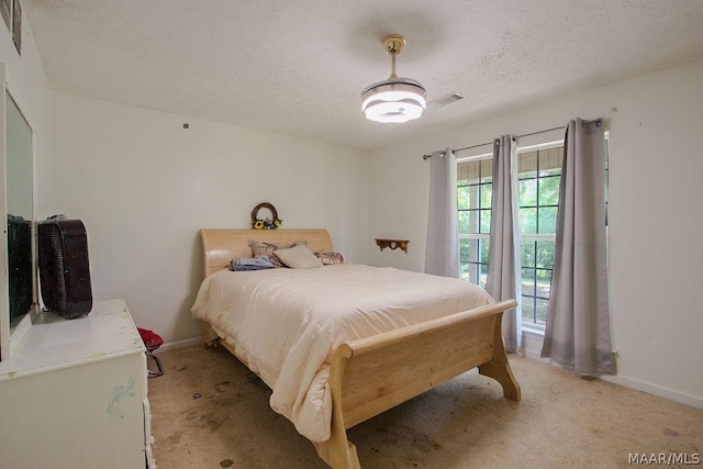 bedroom featuring light colored carpet and a textured ceiling