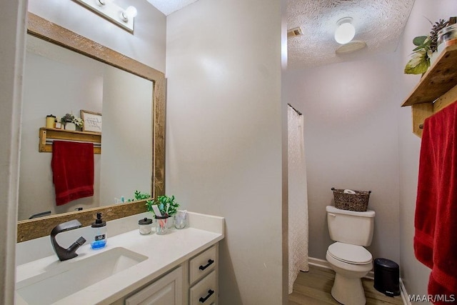 bathroom featuring vanity, a textured ceiling, and toilet