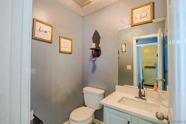 bathroom with vanity, toilet, and a textured ceiling