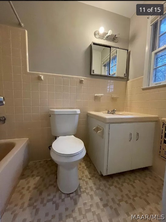 full bathroom with tasteful backsplash, tile patterned flooring, tile walls, toilet, and vanity