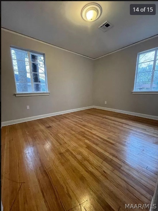 empty room with a healthy amount of sunlight and hardwood / wood-style floors