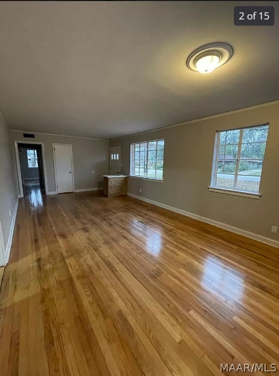 unfurnished living room with light hardwood / wood-style floors and crown molding