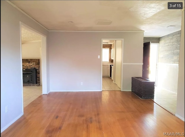 tiled spare room featuring a wood stove, a textured ceiling, and crown molding