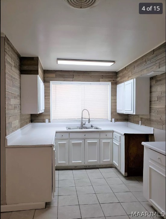 kitchen featuring light tile patterned flooring, sink, and white cabinets