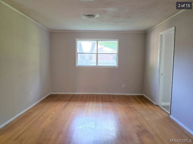 spare room featuring crown molding and light wood-type flooring