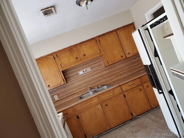 kitchen with sink, fridge, and light tile patterned floors