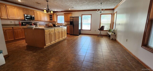 kitchen with appliances with stainless steel finishes, dark tile patterned floors, a notable chandelier, and a center island with sink