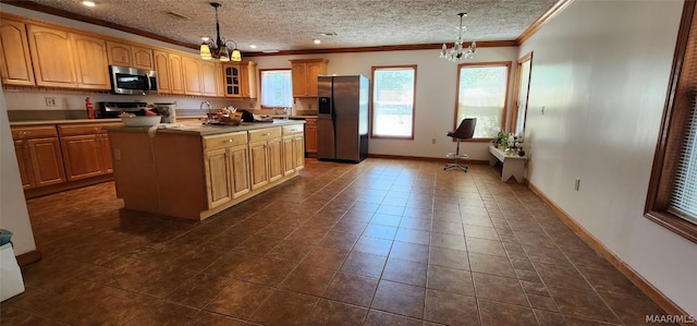 kitchen featuring a chandelier, appliances with stainless steel finishes, glass insert cabinets, and a center island