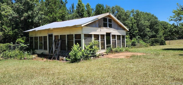 exterior space with a sunroom and a lawn