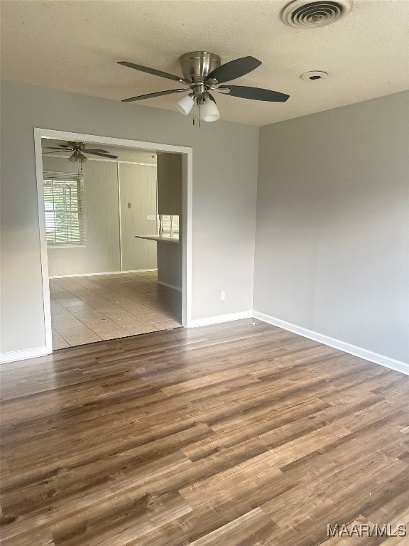 empty room featuring a textured ceiling, wood-type flooring, and ceiling fan