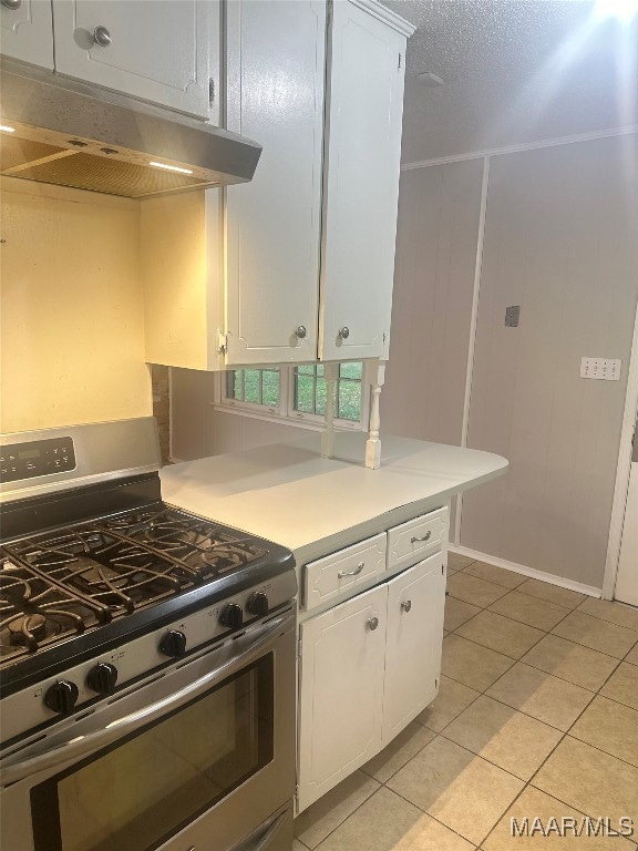 kitchen with white cabinets, light tile patterned floors, and stainless steel range with gas cooktop