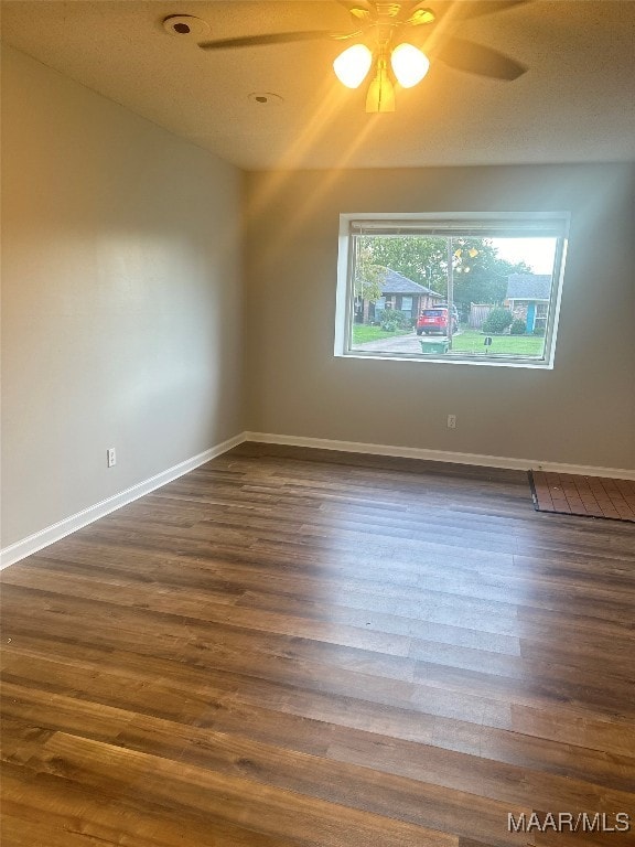 unfurnished room with ceiling fan, a textured ceiling, and dark wood-type flooring