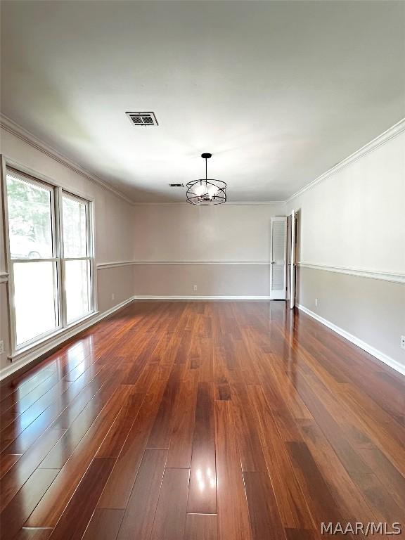 unfurnished room featuring dark wood-type flooring, ornamental molding, and a notable chandelier