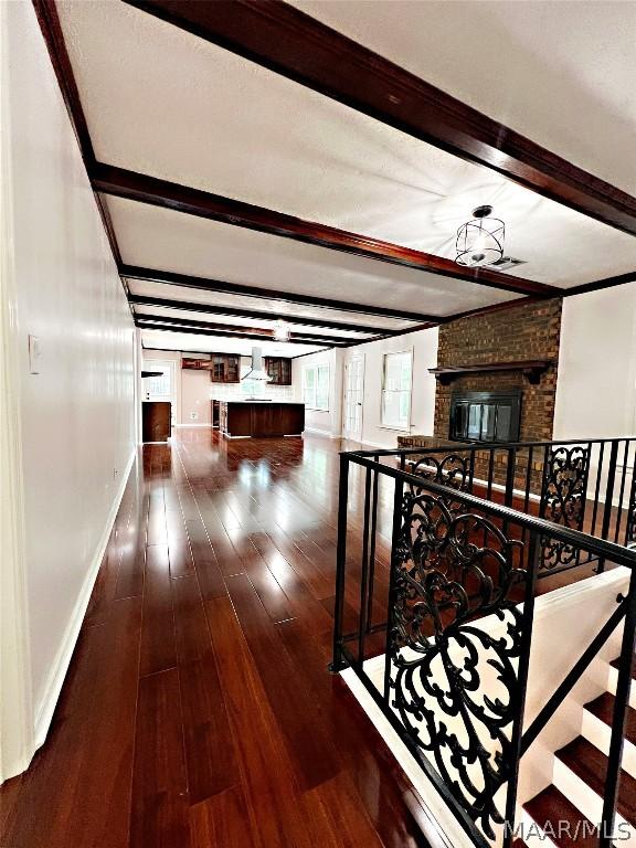 corridor featuring beamed ceiling and dark wood-type flooring