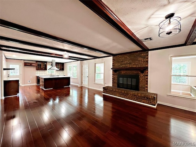 unfurnished living room with beamed ceiling, dark hardwood / wood-style flooring, a textured ceiling, and a fireplace