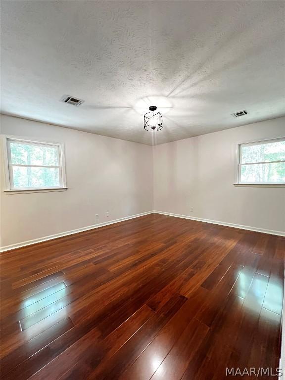 unfurnished room with dark hardwood / wood-style floors and a textured ceiling