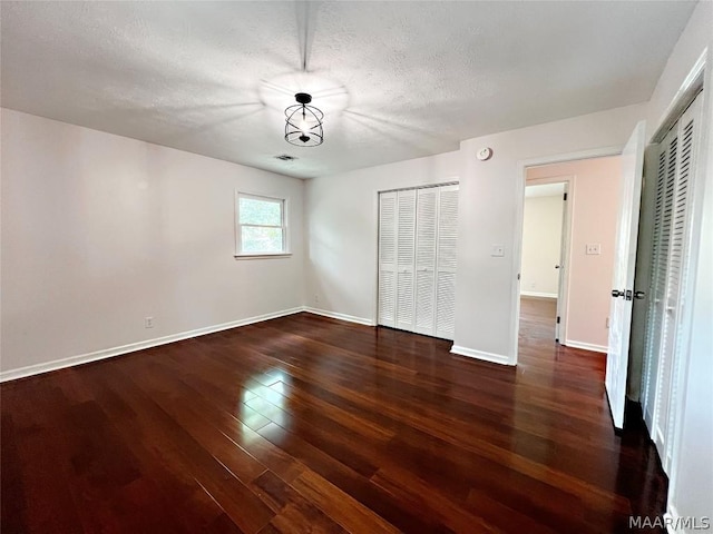 unfurnished bedroom with dark hardwood / wood-style floors and a textured ceiling