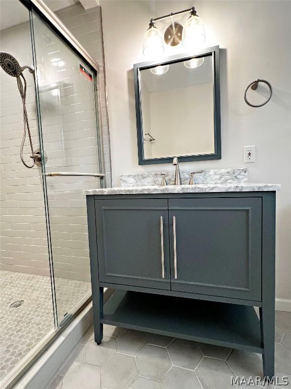 bathroom with a shower with door, vanity, and tile patterned flooring