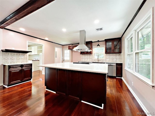 kitchen with dark brown cabinetry, tasteful backsplash, island range hood, dishwasher, and a kitchen island