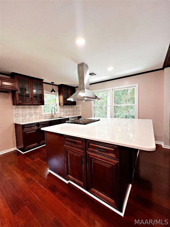 kitchen featuring a kitchen island, island range hood, decorative backsplash, dark wood-type flooring, and dark brown cabinets