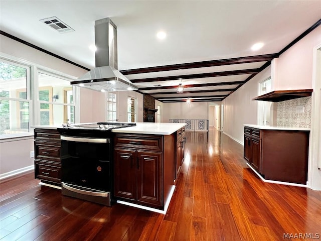 kitchen with beamed ceiling, dark hardwood / wood-style flooring, island exhaust hood, a center island, and electric stove