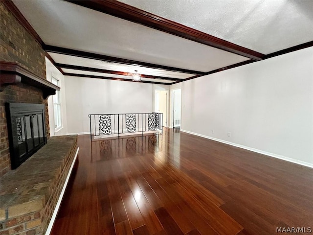 unfurnished living room featuring dark hardwood / wood-style flooring, beam ceiling, a fireplace, and ornamental molding