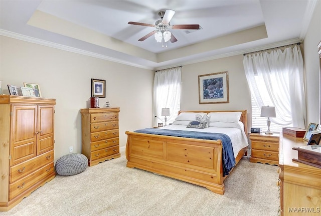 carpeted bedroom with crown molding, ceiling fan, and a tray ceiling