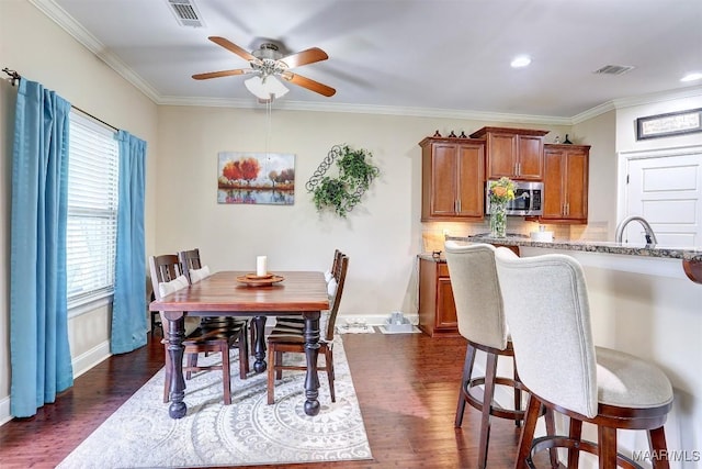 dining room featuring sink, crown molding, dark wood-type flooring, and ceiling fan