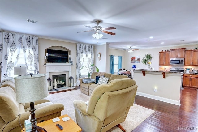 living room with crown molding, ceiling fan, and dark hardwood / wood-style flooring