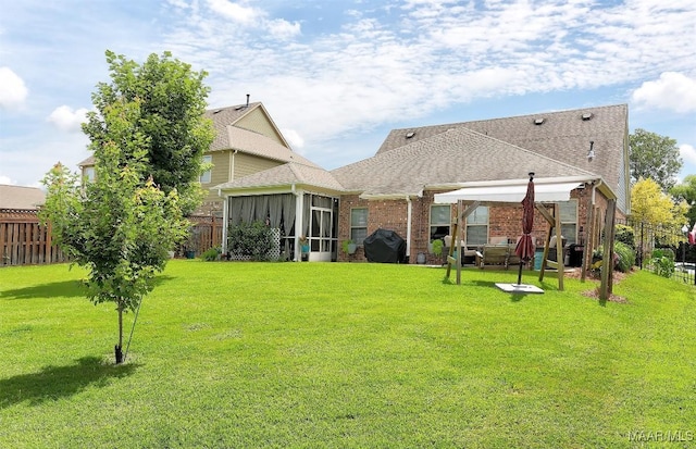 rear view of property featuring a lawn and a sunroom