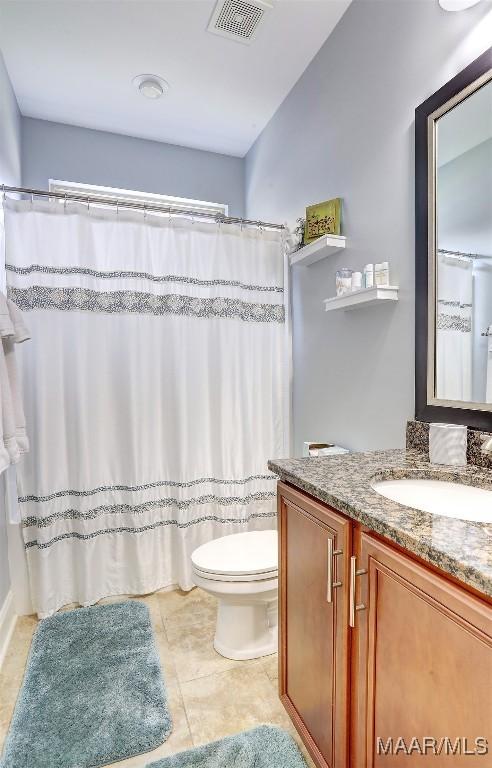 bathroom featuring vanity, tile patterned flooring, toilet, and walk in shower