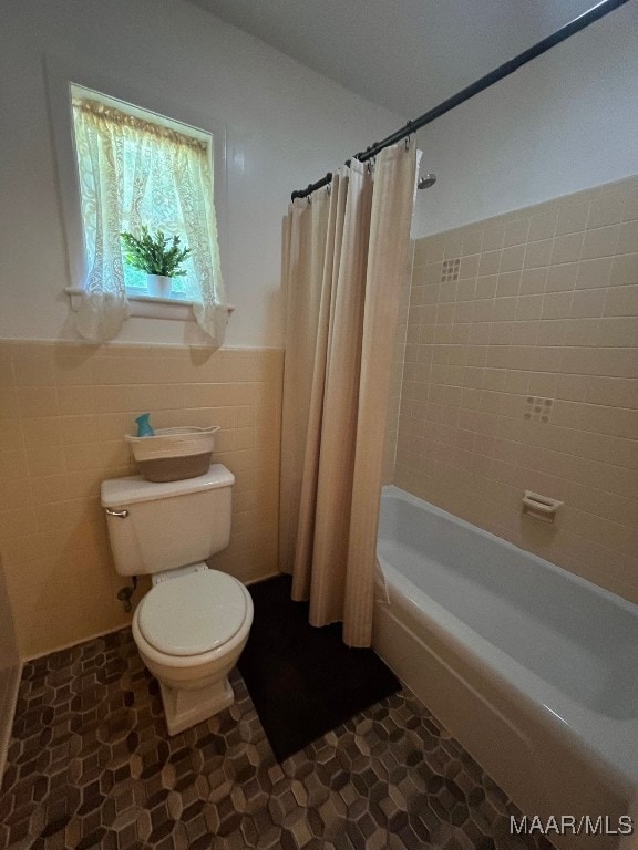 bathroom featuring tile patterned flooring, tile walls, toilet, and shower / tub combo with curtain