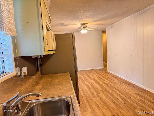 kitchen featuring ceiling fan, sink, a textured ceiling, and light wood-type flooring