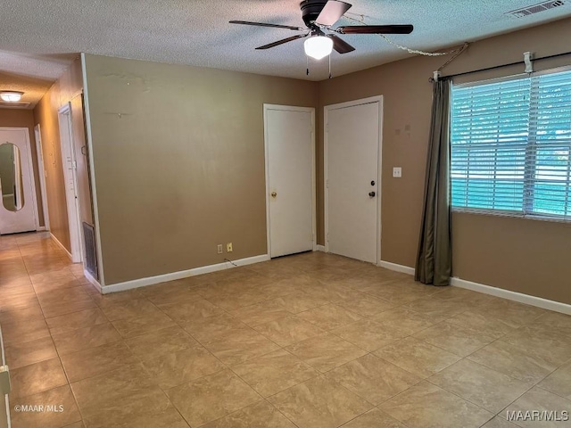 tiled spare room with a textured ceiling, washer / clothes dryer, and ceiling fan