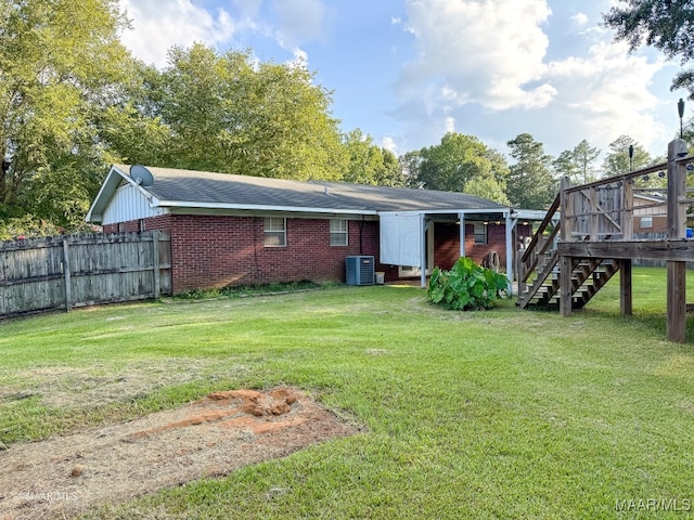 rear view of property featuring central air condition unit, a lawn, and a deck