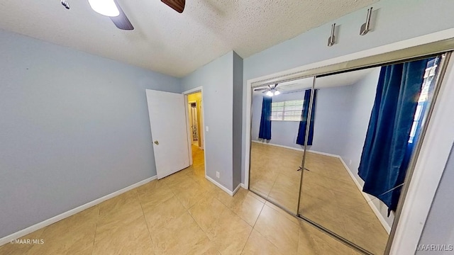 unfurnished bedroom with ceiling fan, light tile patterned floors, a textured ceiling, and a closet