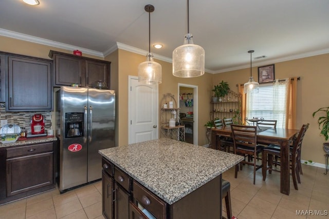 kitchen with hanging light fixtures, dark brown cabinets, stainless steel fridge, and a kitchen island