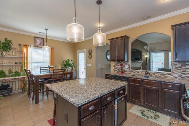 kitchen with dark brown cabinetry, sink, decorative light fixtures, and a kitchen island