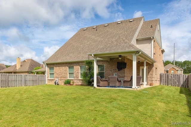 back of house with a fenced backyard, a yard, a shingled roof, brick siding, and ceiling fan