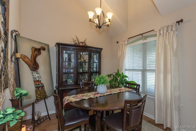 dining space featuring wood-type flooring, vaulted ceiling, and a notable chandelier