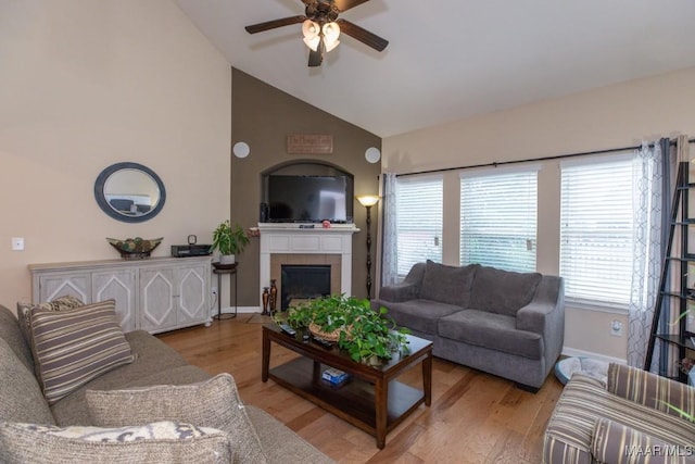 living room featuring a tile fireplace, high vaulted ceiling, ceiling fan, and light wood-type flooring